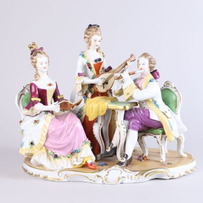 trois figurines représentant des personnes assises autour d'une table et jouant d'instruments de musique