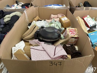 plusieurs cartons remplis de vêtements et d'autres objets posés par terre