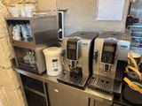 several coffee machines are lined up on a counter in a kitchen