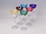 several different colored wine glasses are lined up on a white surface