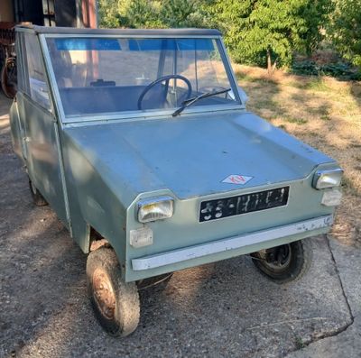 un petit camion vert garé dans l'allée