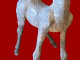 une petite statue représentant un cerf sur fond rouge