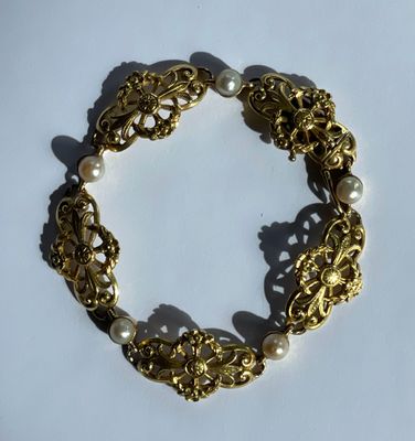 un gros plan d'un bracelet en or orné de perles sur un fond blanc