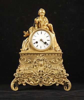 une horloge en or richement décorée posée sur une table noire