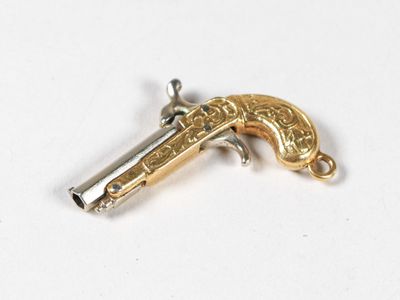 un pendentif en forme de pistolet argenté et doré sur un fond blanc