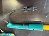 a blue and yellow tool sitting on a table next to a can of soda