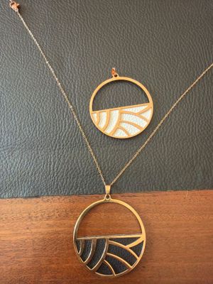 a gold necklace with a black and white design on it