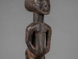 a wooden statue of a man with a head and hands on his chest