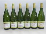 six bottles of wine are lined up on a white surface