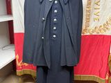 une image représentant un manteau posé sur un mannequin devant un drapeau