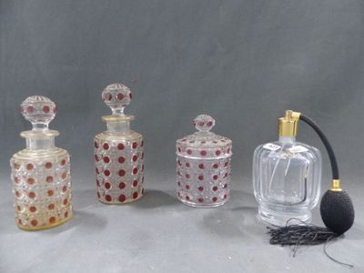 trois flacons de parfum en verre et un objet noir posé sur une surface grise