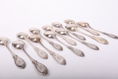 six silver spoons are lined up in a row on a white surface