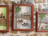 trois tableaux encadrés accrochés à un mur, à côté d'un mur de briques