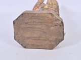 a statue of a man sitting on top of a block of wood