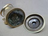 two antique brass candlesticks and a brass cup on a white surface
