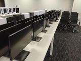 rows of computer desks in an office with computers on them