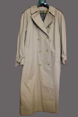 the trench coat is hanging on a hanger on the wall