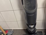 a vacuum that is sitting on the floor next to a broom