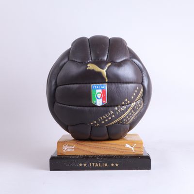 ballon de football en cuir noir posé sur un socle en bois et orné du logo Puma