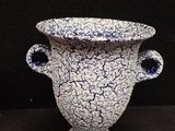 a white and blue vase sitting on a black surface