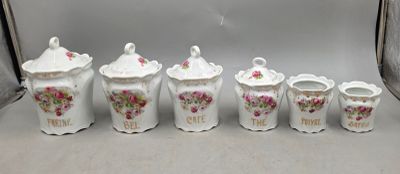 cinq vases blancs ornés de fleurs roses, posés sur une table