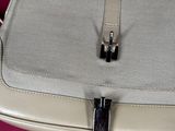 a white purse with a silver handle on a pink surface