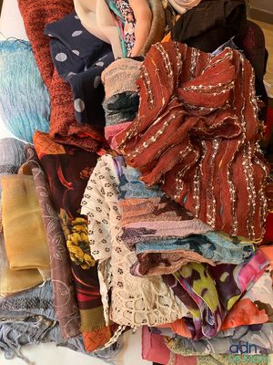 une femme assise sur un lit, avec une pile de vêtements à côté d'elle