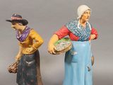 two figurines of women with baskets and a man holding a basket
