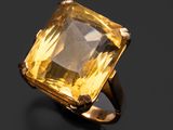 un gros plan d'une bague ornée d'une pierre jaune sur un fond noir