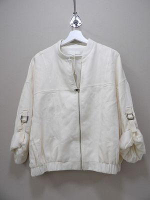 the white jacket is hanging on a hanger on the wall
