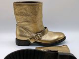 a pair of gold leather boots with buckles and a black sole