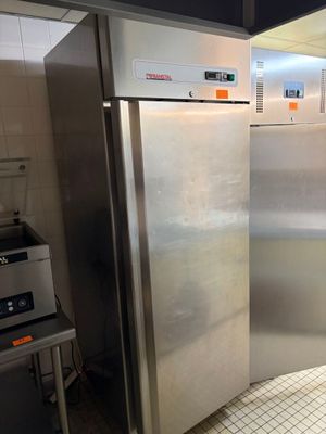 un réfrigérateur en acier inoxydable dans une cuisine au sol carrelé