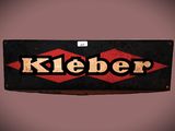 Une vieille enseigne portant l'inscription « Kleber » est accrochée à un mur.