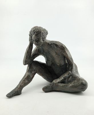 statue of a man sitting on the ground with his hand on his head