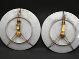 two white plates with gold numbers on them on a black surface