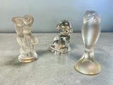 trois figurines en verre posées sur une table