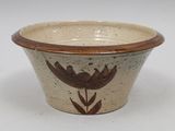 a brown and white bowl with a flower design on it