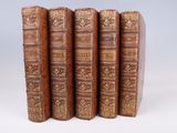 six vieux livres sont alignés sur une surface blanche