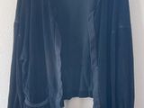 un cardigan noir suspendu à un cintre devant un mur blanc
