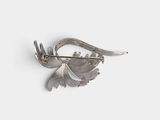 an image of a silver brooch with a bird on it