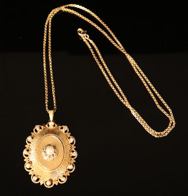 a close up of a gold necklace with a diamond in the center