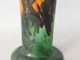 a green vase with a painting on it on a table