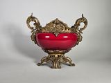 un vase rouge orné d'un motif doré sur le dessus