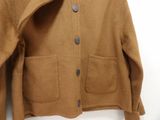 brown wool jacket hanging on a hanger against a white wall