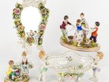 trois figurines en porcelaine représentant des personnages et un miroir posés sur une table