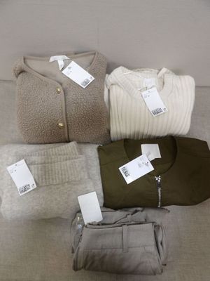 quatre paires de pulls et un sac à main sont posés sur un canapé