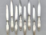 six silverplated knives and a knife holder on a table