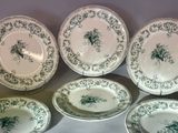 six green and white plates with a bird on them on a table