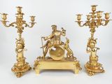 three gold colored candlesticks with a statue on top of them