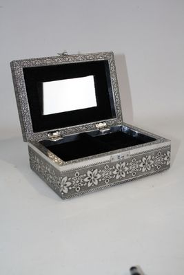 une boîte en argent contenant un miroir, posée sur une table